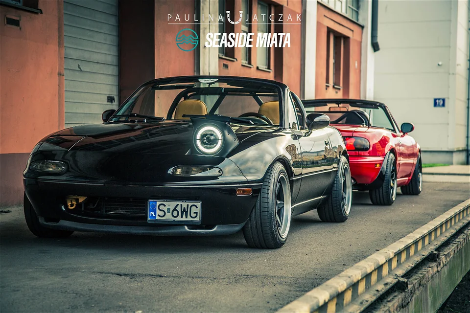 Czarna i czerwona Mazda MX-5 NA z otwartymi dachami