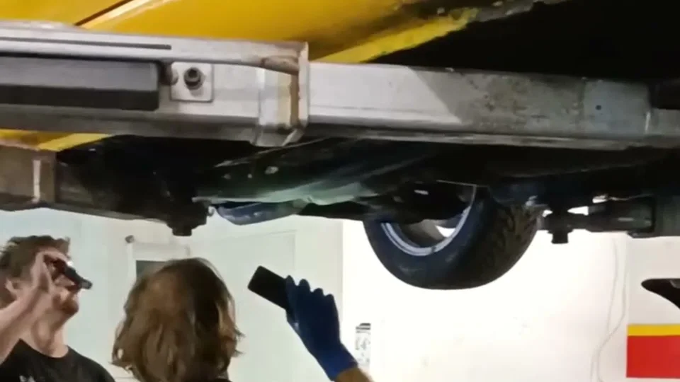 Mechanicy podczas oględzin podwozia samochodu na podnośniku